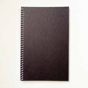 Pode incluir: Um caderno preto de espiral com capa texturizada.