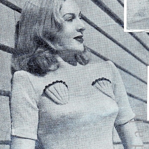 Puede incluir: Una mujer lleva un suéter gris claro con un diseño festoneado en la parte delantera. Está sosteniendo un par de gafas de sol en su mano.