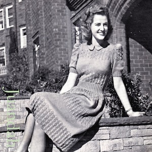May include: A black and white photo of a woman wearing a knitted dress with a collared neckline. She is sitting on a stone wall with her legs crossed. The dress has a textured pattern and the woman is wearing heels. The photo is from a vintage magazine and includes the text "DESIGN No. 2691".