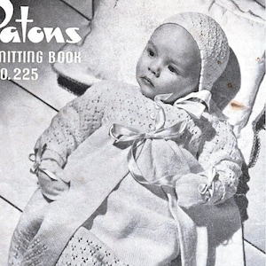 May include: A black and white photo of a baby wearing a white crocheted dress and bonnet. The baby is lying on a white surface and the dress has a lace pattern. The photo is from a vintage knitting book.