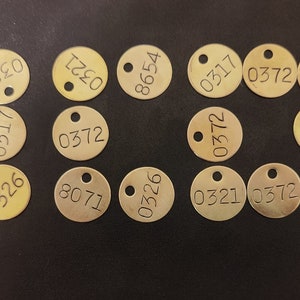 May include: A collection of round, brass tags with various numbers printed on them. The numbers include 0317, 8071, 0321, 8654, 0326, 2120, 0326, 0321, 3372, 8654, 0372, 0317, 0372, 0326, 8071, 0321, 0317, 0321, 0372, 8658654, 0326, 0317, 0321, 8654, 8071, 8071, 0372.