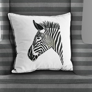 May include: A white throw pillow with a black and white zebra head design on a gray striped armchair. The armchair has wooden legs. The text "Lily's Embroidery Designs" is on a green rectangle in the lower right corner of the image.
