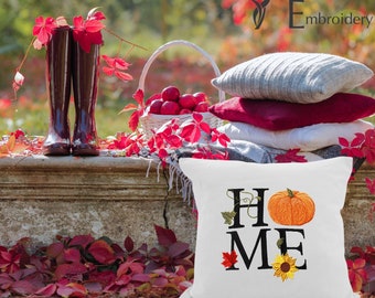 May include: White throw pillow with the word "HOME" embroidered in black with autumn-themed accents including a pumpkin, sunflower, and maple leaf.