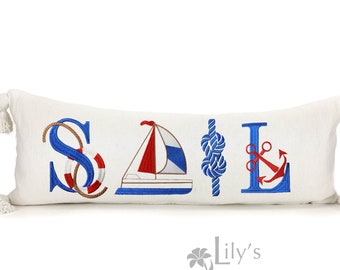 以下が含まれることがあります： 白地に青と赤で「SAIL」と刺繍された長方形の枕。文字は救命胴衣、帆船、結び目、錨などの海事のシンボルで飾られています。