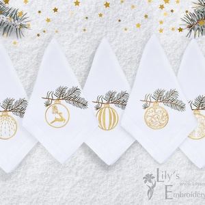Può includere: Cinque tovaglioli bianchi con ornamenti natalizi ricamati in oro appesi a un ramo di pino. Gli ornamenti sono di diversi design, tra cui una renna, una palla a strisce e un design a spirale.