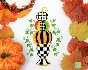 Puede incluir: Una pila de tres calabazas en un jarrón a cuadros blanco y negro con enredaderas verdes. Las calabazas están decoradas con lunares blancos y negros, rayas blancas y negras y rayas rojas, amarillas y verdes.