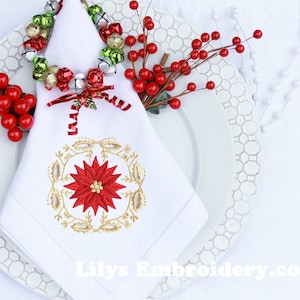 Könnte beinhalten: Weiße Serviette mit einem goldenen und roten gestickten Weihnachtsstern-Design. Die Serviette ist gefaltet und mit einem Ring aus goldenen, grünen und silbernen Glocken mit einem roten Band zusammengehalten.