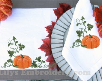 May include: Embroidered white linen placemats and napkins with an autumn theme. The design features a pumpkin vine with green leaves and orange pumpkins. The placemats and napkins are accented with autumn-coloured leaves.