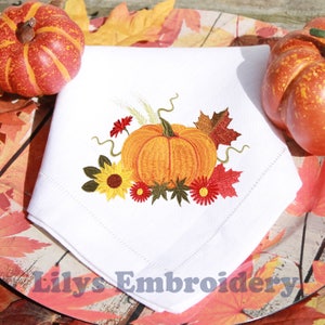 May include: White cloth napkin with an embroidered autumn design. The design features a large orange pumpkin, yellow sunflowers, red flowers, and fall leaves. The text "Lilys Embroidery" is at the bottom.