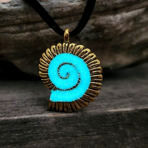 May include: A gold-tone necklace with a glow-in-the-dark blue spiral shell pendant. The pendant is shaped like a nautilus shell.
