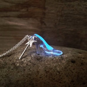 Pu&ograve; includere: Una collana d'argento con un ciondolo a forma di scarpetta di vetro e un ciondolo a forma di bacchetta magica d'argento. La scarpetta &egrave; trasparente e brilla di blu al buio.