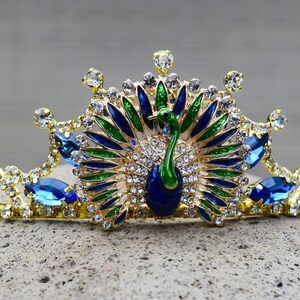 May include: A gold crown with blue and green peacock feathers and rhinestones.