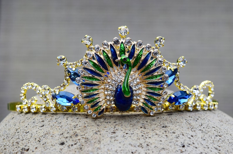 May include: A gold crown with blue and green peacock feathers and rhinestones.