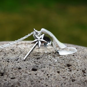 Pu&ograve; includere: Una collana d'argento con un ciondolo a forma di scarpetta di vetro e un ciondolo a forma di bacchetta magica con una stella in cima.