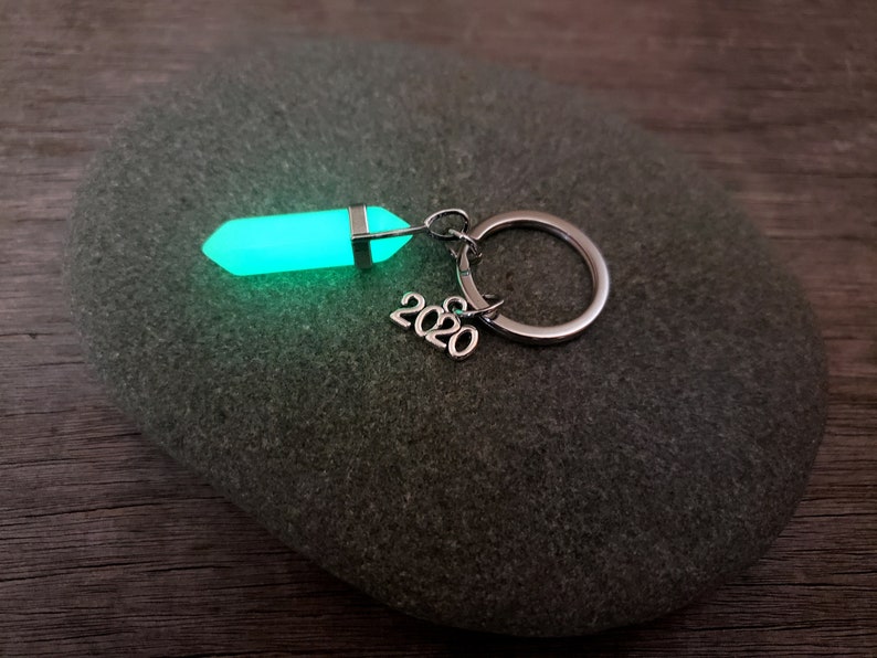 May include: A green glow-in-the-dark crystal keychain with a silver ring and the year 2020 attached.