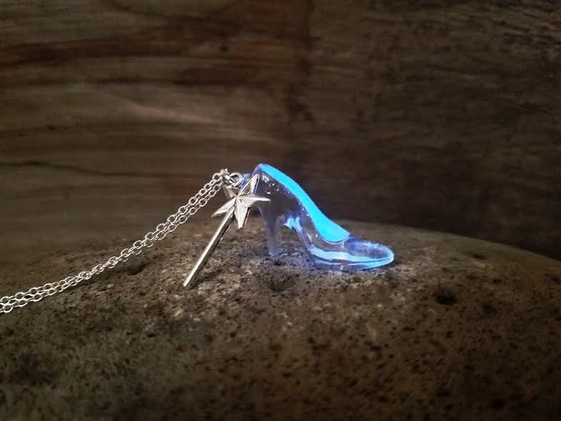 Pu&ograve; includere: Una collana d'argento con un ciondolo a forma di scarpetta di vetro e un ciondolo a forma di bacchetta magica d'argento. La scarpetta &egrave; trasparente e brilla di blu al buio.