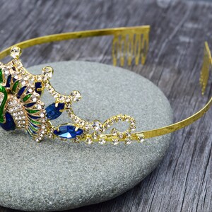 May include: Gold peacock headband with blue and green enamel and clear rhinestones. The headband has a comb on the back for easy attachment.