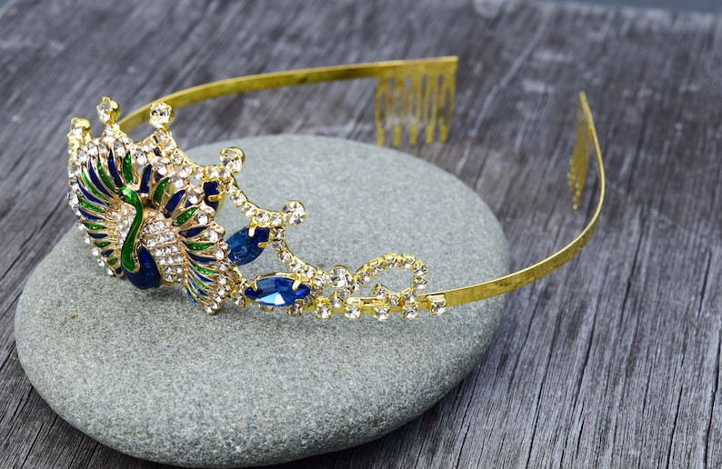 May include: Gold peacock headband with blue and green enamel and clear rhinestones. The headband has a comb on the back for easy attachment.