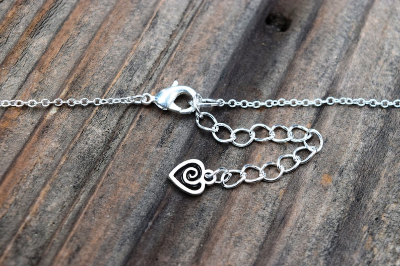 Puede incluir: Collar de cadena de plata con cierre de langosta y un dije en forma de coraz&oacute;n con un dise&ntilde;o de espiral.