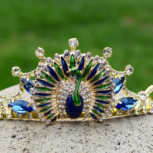 May include: A gold crown with blue and green peacock feathers and rhinestones.
