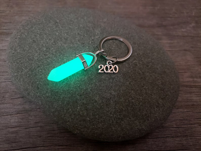 May include: A silver key chain with a glowing green crystal charm and a silver charm with the year 2020.