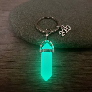 May include: A silver key chain with a glow-in-the-dark green crystal pendant and a silver charm that says "2020".