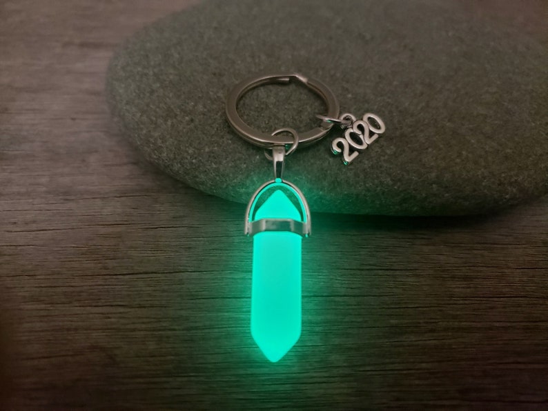 May include: A silver key chain with a glow-in-the-dark green crystal pendant and a silver charm that says "2020".
