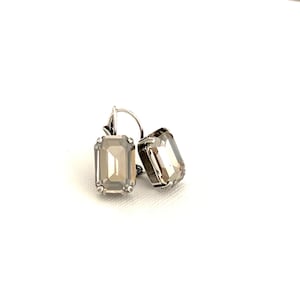 May include: A pair of silver earrings with clear, rectangular, faceted stones.