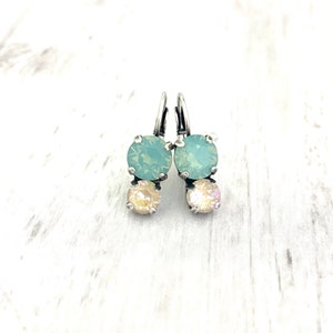 May include: A pair of silver dangle earrings with two light blue and two light pink round crystals.