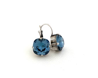 May include: A pair of silver dangle earrings with a square blue crystal stone.