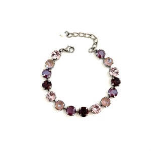 May include: A silver chain bracelet with a row of round, faceted crystals in shades of pink and purple.