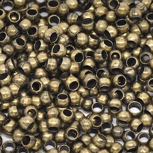 May include: A large quantity of small, round, gold-coloured metal beads. The beads have a smooth, slightly textured surface and a hole in the centre.