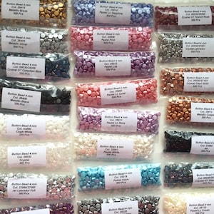 May include: A selection of 4mm button beads in diverse colours, packaged in clear plastic bags. Colours include metallic brass, silver, black, white, and pastel shades such as pink, lilac, and aqua. Each bag contains 300 pieces.