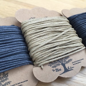 May include: Three spools of cord in shades of blue and beige, each on a brown card. The cards feature a tree design and the text "To the world". The cord is tightly wound, indicating it is new. Ideal for crafts.