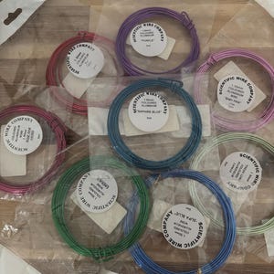 May include: A collection of colorful aluminum wire spools in various shades, including pink, purple, blue, and green. Each spool is labeled with the "Scientific Wire Company" logo and color name. The wire is 1.50mm thick.