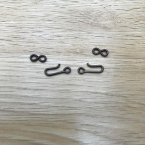 May include: Four silver-toned metal jewellery findings, two are infinity symbols and two are open jump rings.