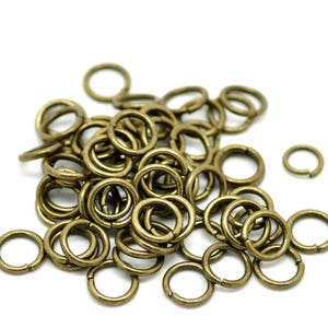 May include: A pile of antique gold jump rings, a type of metal ring used in jewellery making.