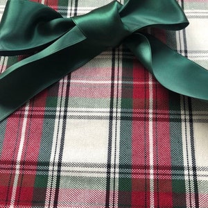 Puede incluir: Una cinta de sat&eacute;n verde atada en un lazo sobre una tela de cuadros rojos, verdes y blancos.