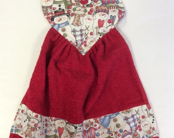 Peut inclure: Serviette de cuisine rouge en forme de cœur avec un imprimé de bonhomme de neige. La serviette a une boucle pour accrocher et un bouton.
