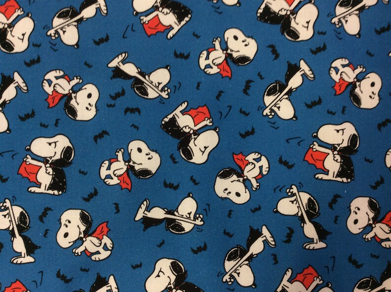 Peut inclure: Un tissu bleu avec un motif r&eacute;p&eacute;t&eacute; d'un chien de dessin anim&eacute; d&eacute;guis&eacute; en vampire. Le chien porte une cape noire et un collier rouge. Il y a aussi de petites chauves-souris noires &eacute;parpill&eacute;es sur le tissu.