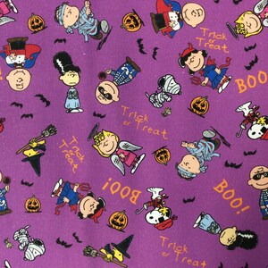 Peut inclure: Tissu violet avec un motif r&eacute;p&eacute;t&eacute; de personnages de Peanuts habill&eacute;s en costumes d'Halloween. Les personnages incluent Snoopy, Charlie Brown, Lucy et Linus. Le tissu pr&eacute;sente le texte "Trick or Treat" et "Boo!" r&eacute;p&eacute;t&eacute; sur toute sa surface.