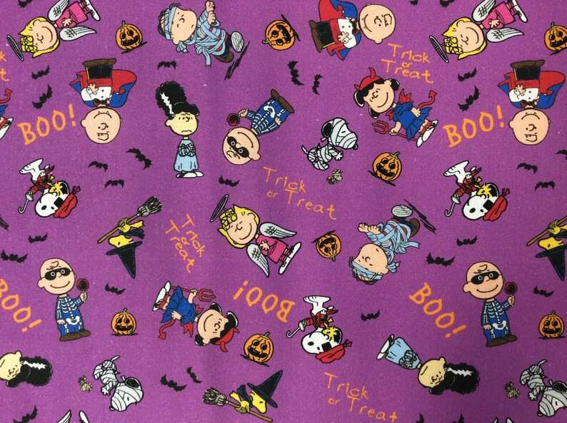 Peut inclure: Tissu violet avec un motif r&eacute;p&eacute;t&eacute; de personnages de Peanuts habill&eacute;s en costumes d'Halloween. Les personnages incluent Snoopy, Charlie Brown, Lucy et Linus. Le tissu pr&eacute;sente le texte "Trick or Treat" et "Boo!" r&eacute;p&eacute;t&eacute; sur toute sa surface.