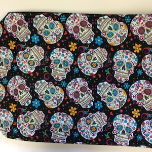 May include: Black fabric with a repeating pattern of colorful sugar skulls with floral designs.