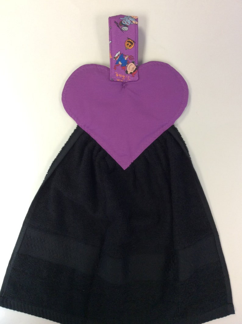 Peut inclure: Porte-serviette en forme de c&oelig;ur violet avec une serviette noire suspendue. Le porte-serviette a une boucle en tissu avec un imprim&eacute; sur le th&egrave;me d'Halloween.