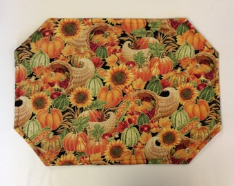Peut inclure: Un set de table rectangulaire en tissu aux coins coupés, orné d'un motif automnal répétitif sur fond noir. Le design présente des citrouilles orange, des courges vertes, des tournesols jaunes, des cornes d'abondance et des feuilles d'automne.