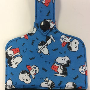Peut inclure: Une serviette de cuisine bleue avec un bouton noir et une boucle de suspension. La serviette pr&eacute;sente un motif r&eacute;p&eacute;t&eacute; de Snoopy d&eacute;guis&eacute; en vampire avec une cape rouge et des chauves-souris.