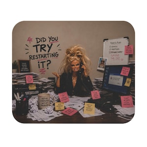 May include: A mouse mat showing a doll at a cluttered desk, on the phone. The text "DID YOU TRY RESTARTING IT?" is above her. Sticky notes and a mug that says "NOT MY COMPUTER NOT MY PROBLEM" are visible.