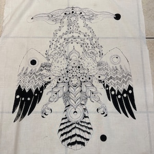 Może przedstawiać: Kremowa tkanina z dużym czarno-białym graficznym przedstawieniem stylizowanego orła. Orzeł ma szczeg&oacute;łowe skrzydła, szpony i centralny wz&oacute;r ciała z elementami okrągłymi i krzyżowymi. Grafika jest symetryczna i skomplikowana.