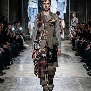 Puede incluir: Un blazer de texturas múltiples que presenta un panel de tweed marrón, una sección de cuadros rojos y verdes y una manga a rayas blancas y negras. La prenda incluye una hilera de botones coloridos, un bolsillo en el pecho y una estructura.