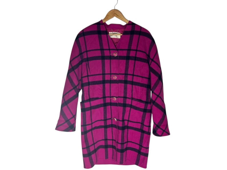 May include: A magenta and black plaid coat with a classic design. The coat features a collared neckline, three buttons, and two front pockets. The coat is hanging on a wooden hanger.